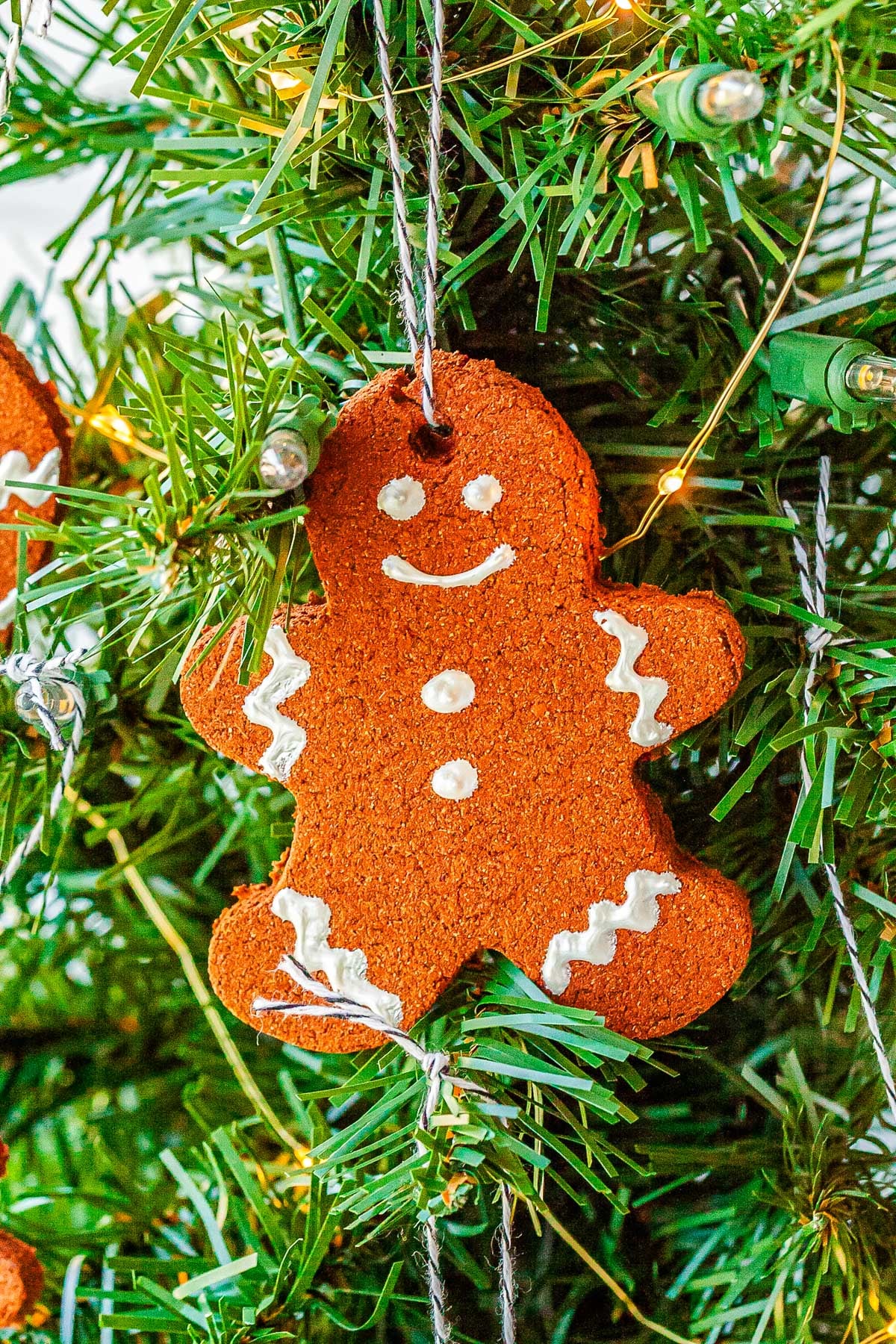 A gingerbread cinnamon ornament hanging from a Christmas tree. 