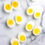 An overhead picture of Hard Boiled Eggs cut in half, all cooked to different doneness.