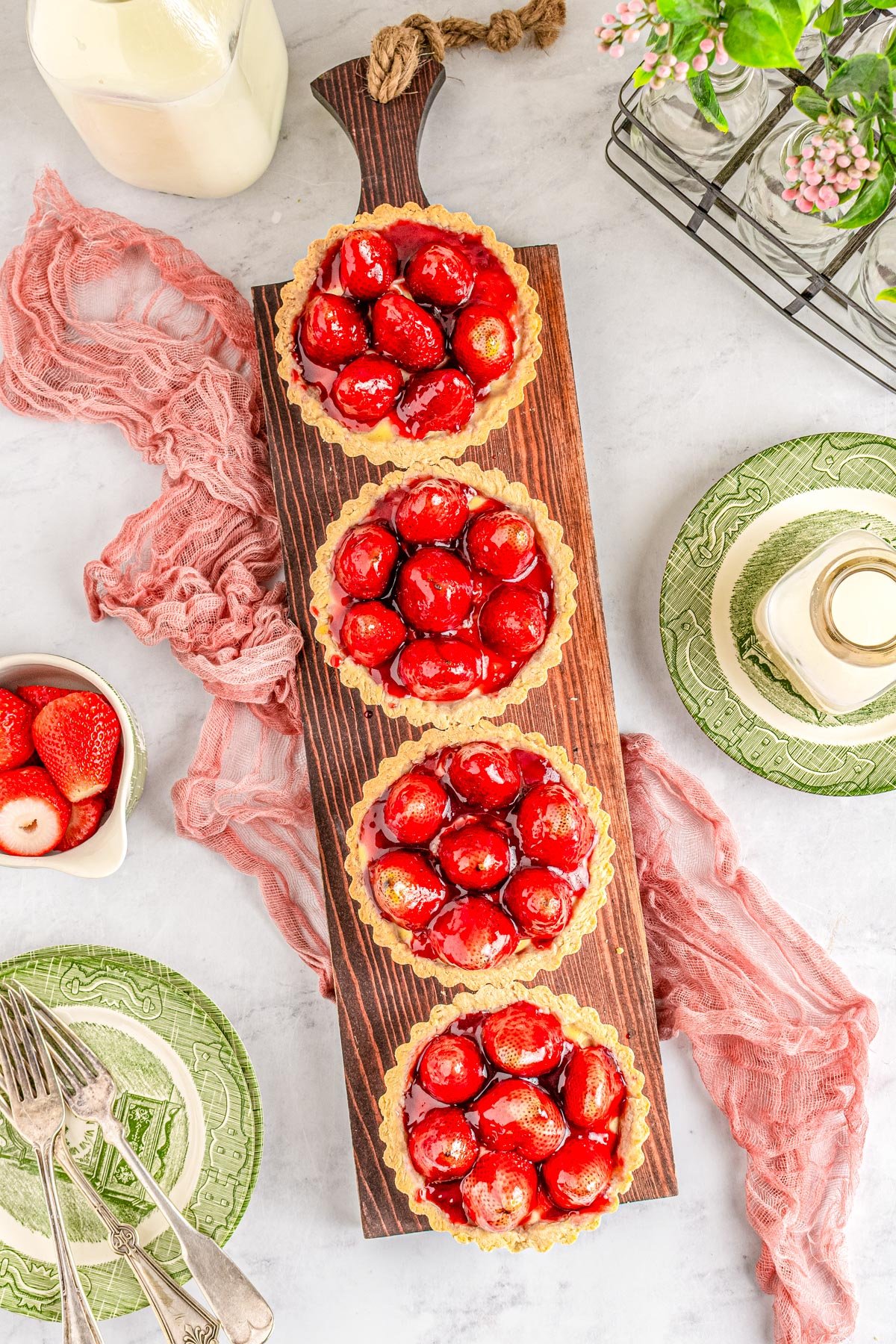 An overhead picture of four Strawberry Tartlets on a wooden serving board. 