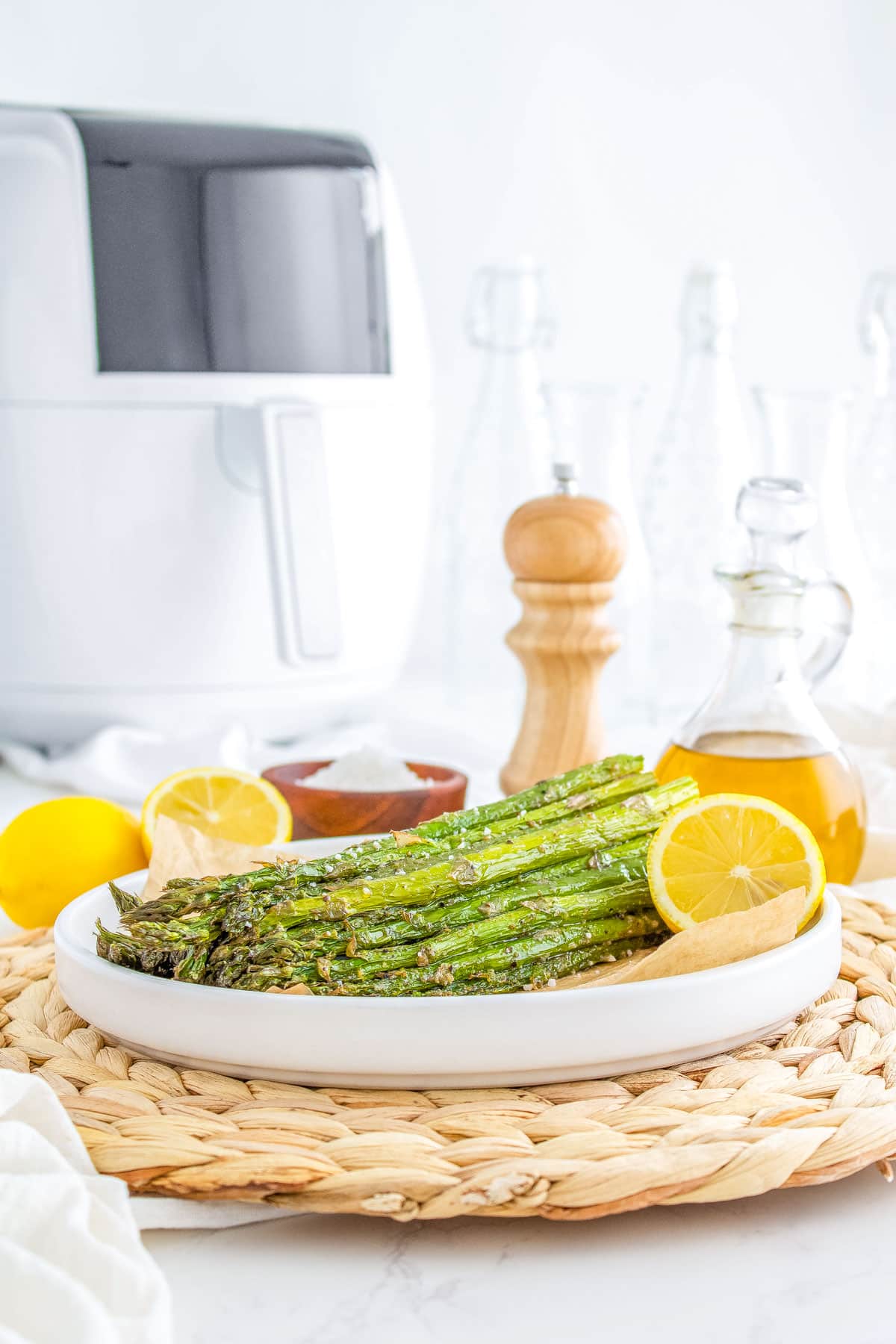 The finished Air Fryer Asparagus on a white platter garnished with lemon wedges.