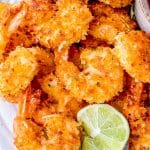 A plate of Coconut Shrimp with lime wedges.