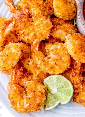 A plate of Coconut Shrimp with lime wedges.