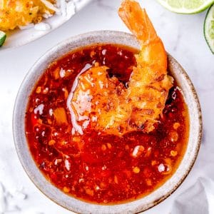 A close up picture of Coconut Shrimp being dunked into sauce.