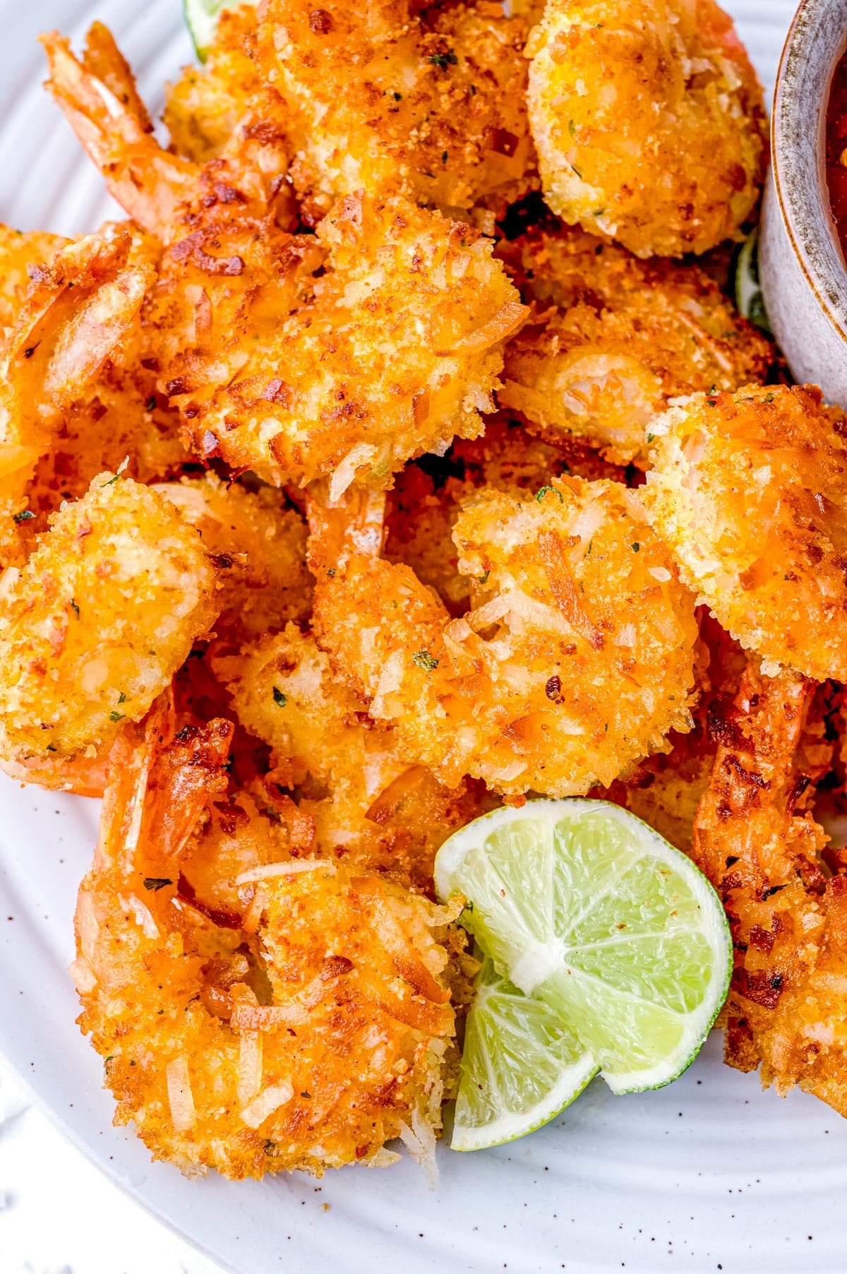 A plate of Coconut Shrimp with lime wedges. 