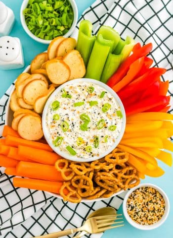 An overhead picture of Everything But The Bagel Dip on a serving platter with bagel chips and veggies.