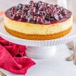 The finished Homemade Cherry Cheesecake on a white cake stand.