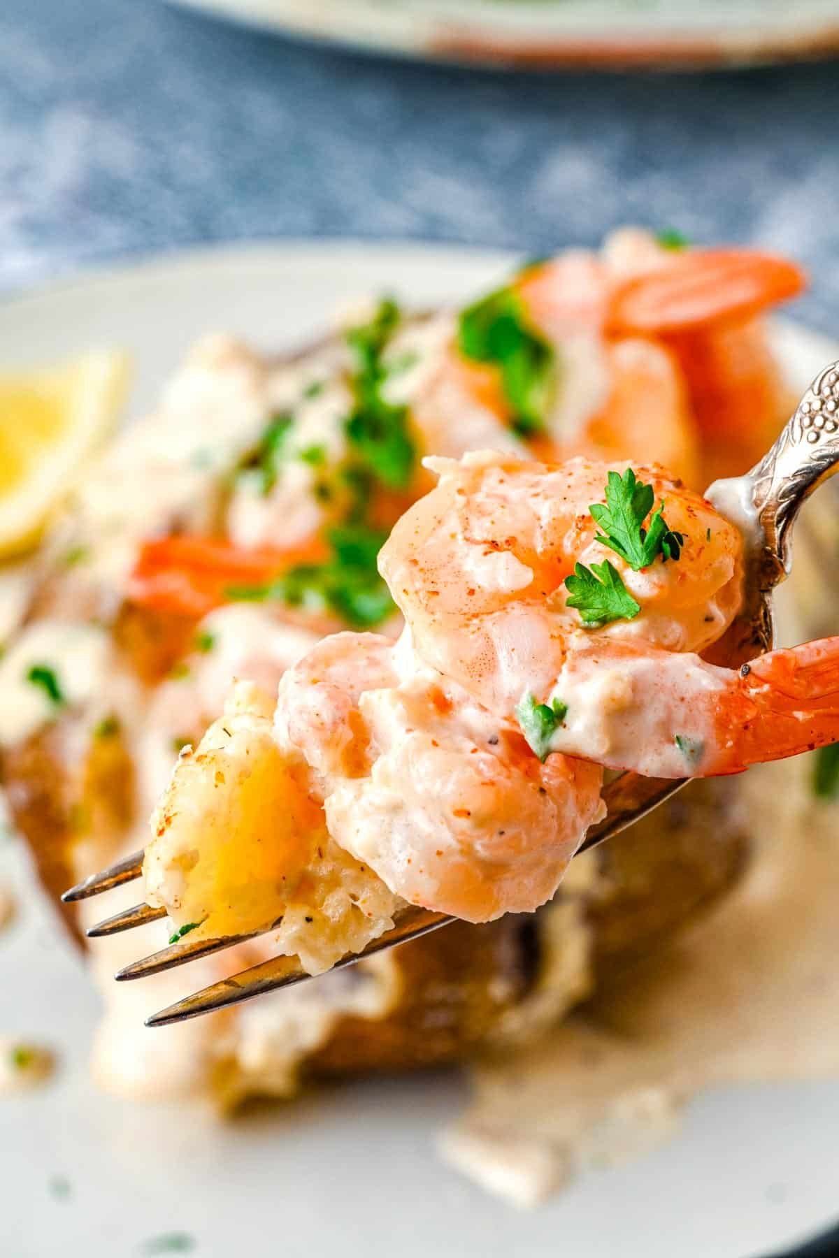 A fork taking a forkful out of a Loaded Shrimp Baked Potato.