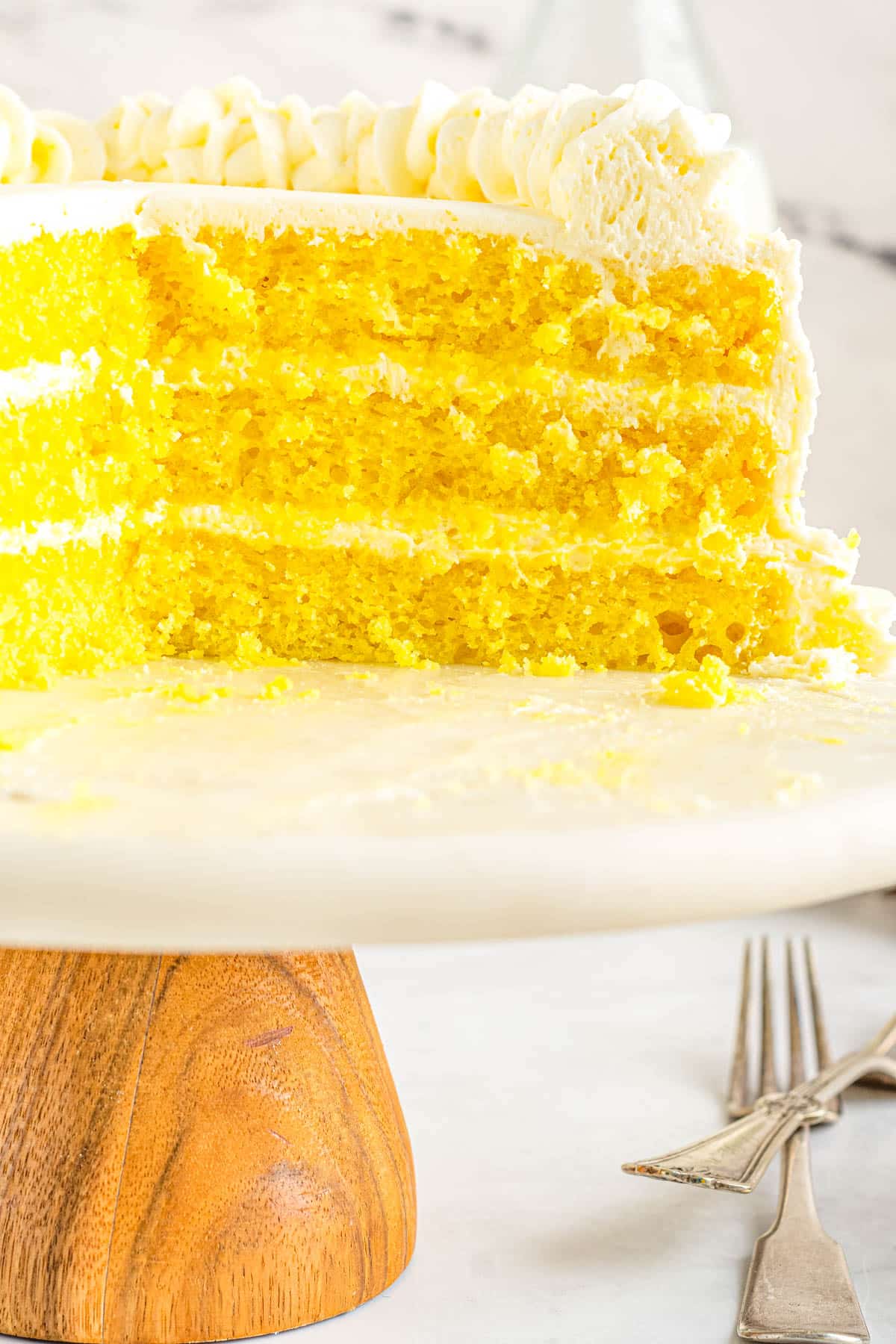 The recipe for Lemon Velvet Cake on a cake stand. The cake has been cut into so you can see all the layers.