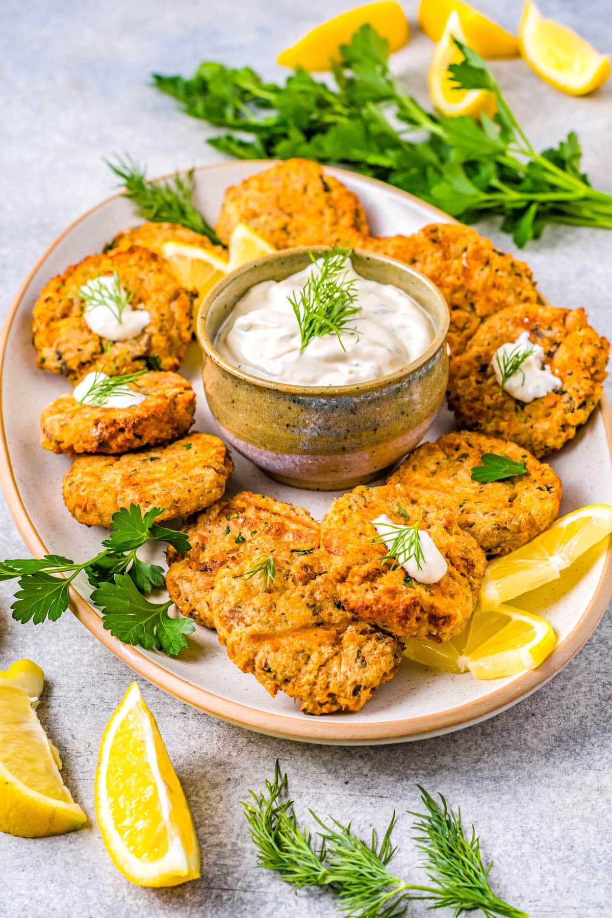 The Air Fryer Salmon Patties on a platter with dill dipping sauce and lemon wedges.