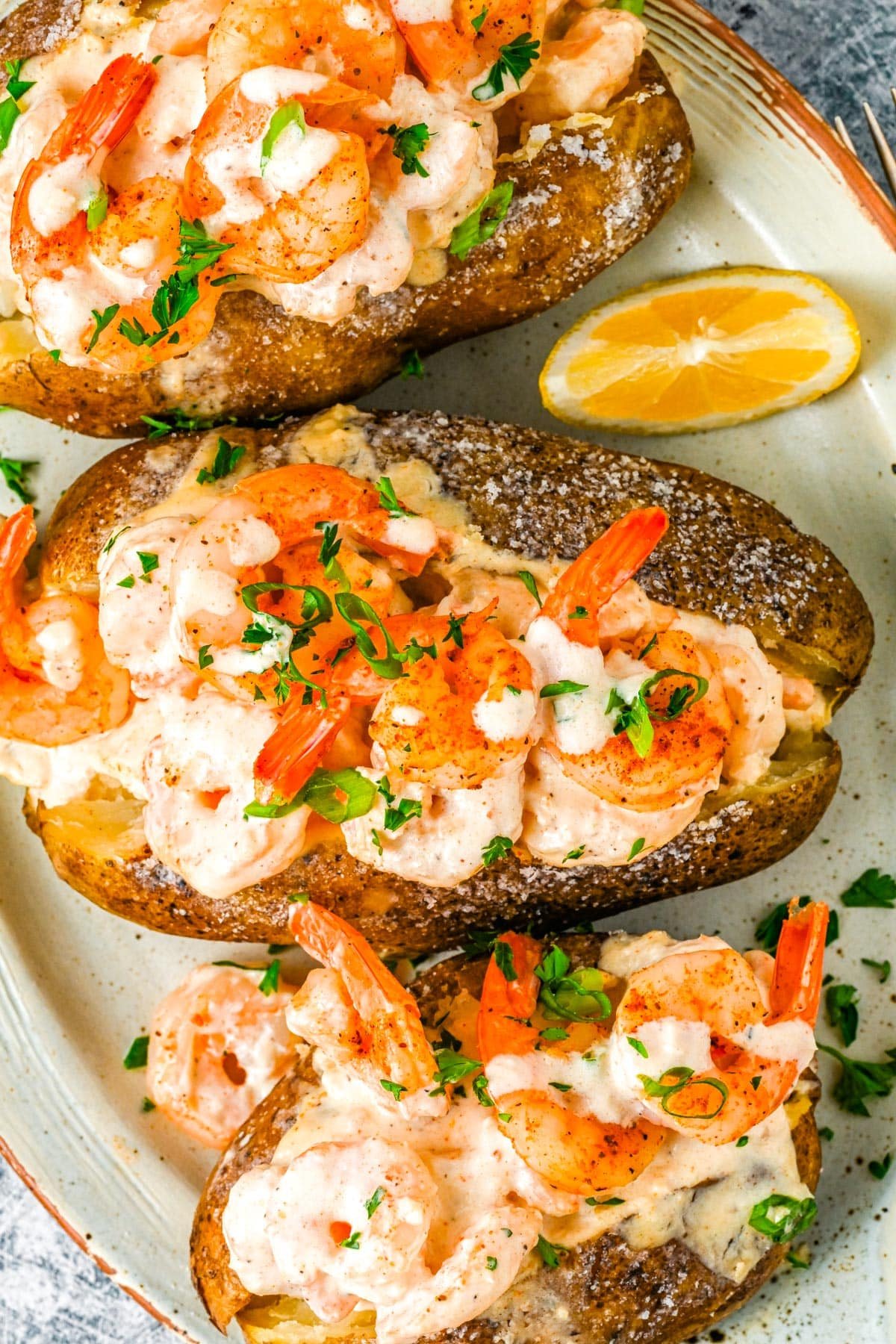A close up of a Shrimp Baked Potato on a white plate. 
