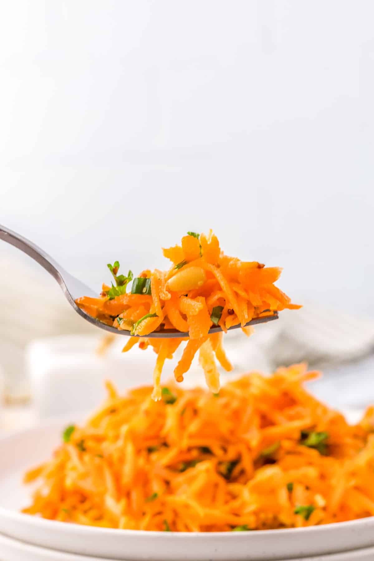 A fork picking up some of the finished Raw Carrot Salad.