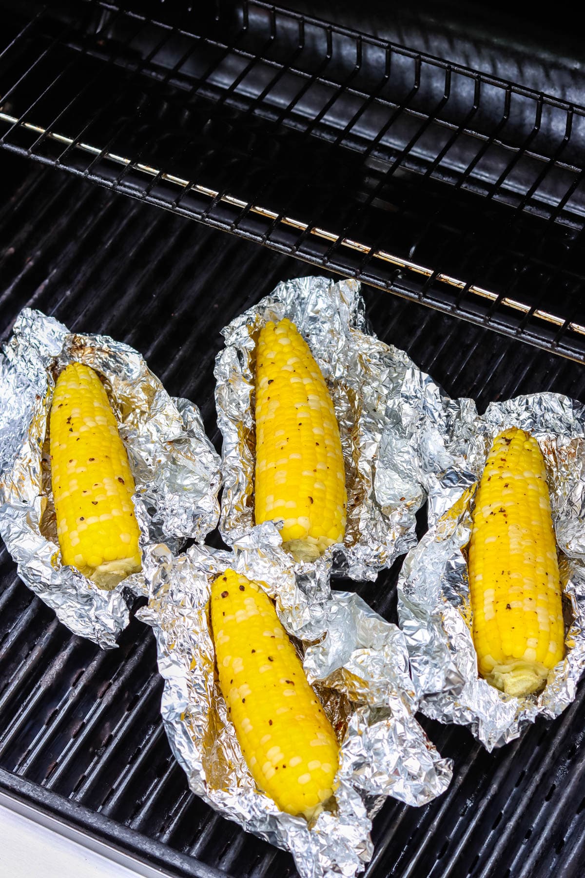 An overhead picture of grilled corn in foil on the grill.