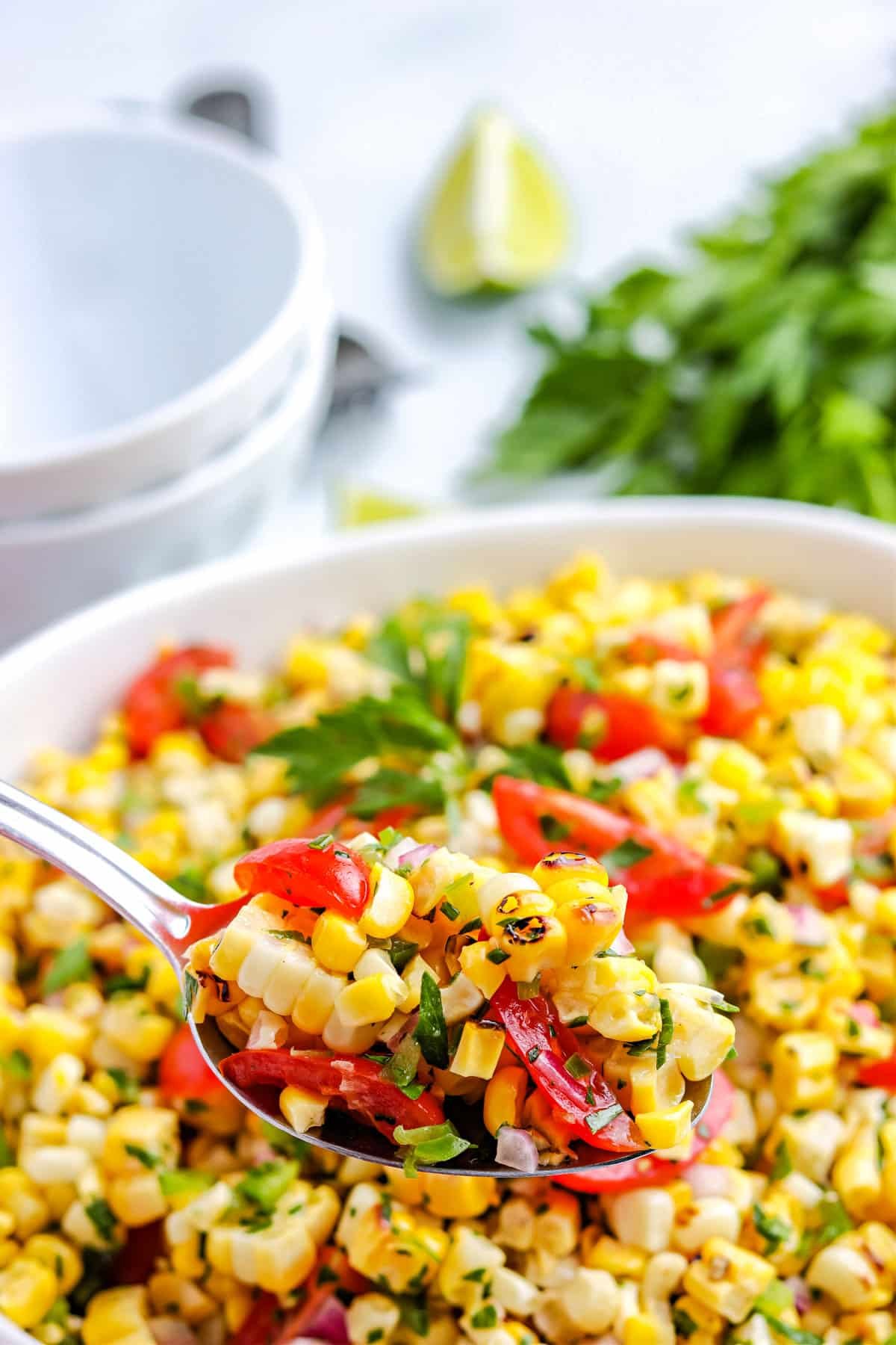 A spoon scooping up some of the corn salad that's been grilled.