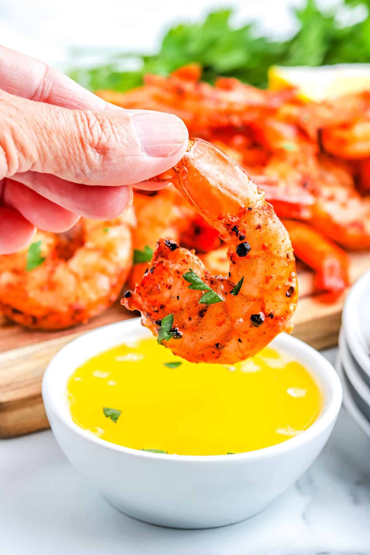 A smoked shrimp being dipped into clarified butter.