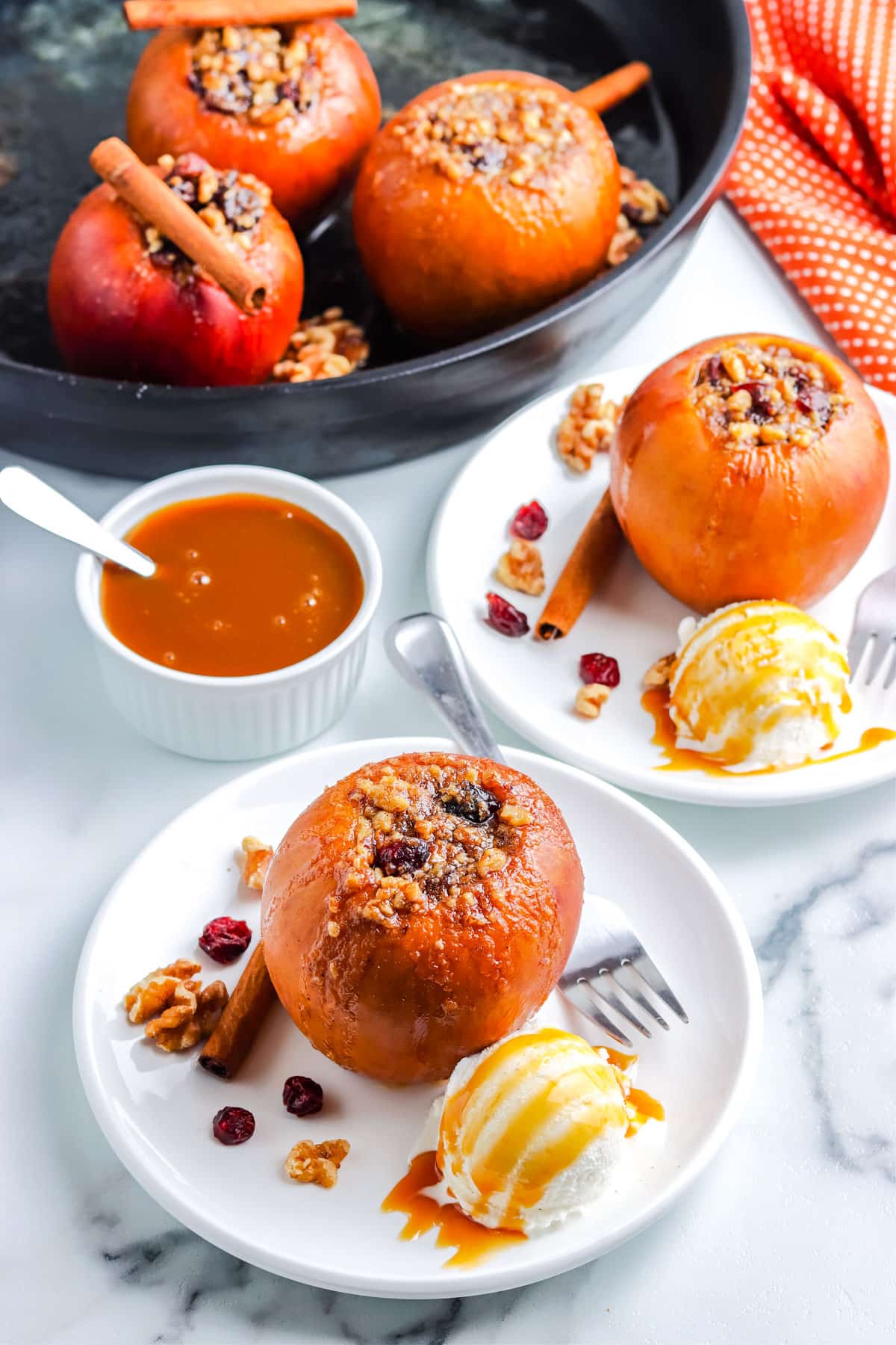 Smoked Apples on white plates with scoops of vanilla ice cream and caramel sauce.
