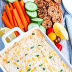 An overhead picture of the finished Hot Crab Dip with carrots, cucumber, pretzels, and crackers surrounding it.