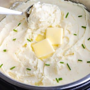 A serving spoon scooping some of the finished mashed potatoes in an instant pot.