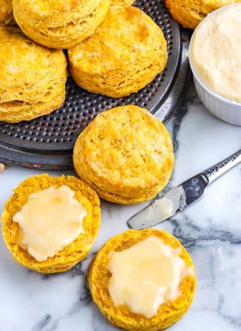 A pumpkin biscuit cut in half and covered in honey butter.