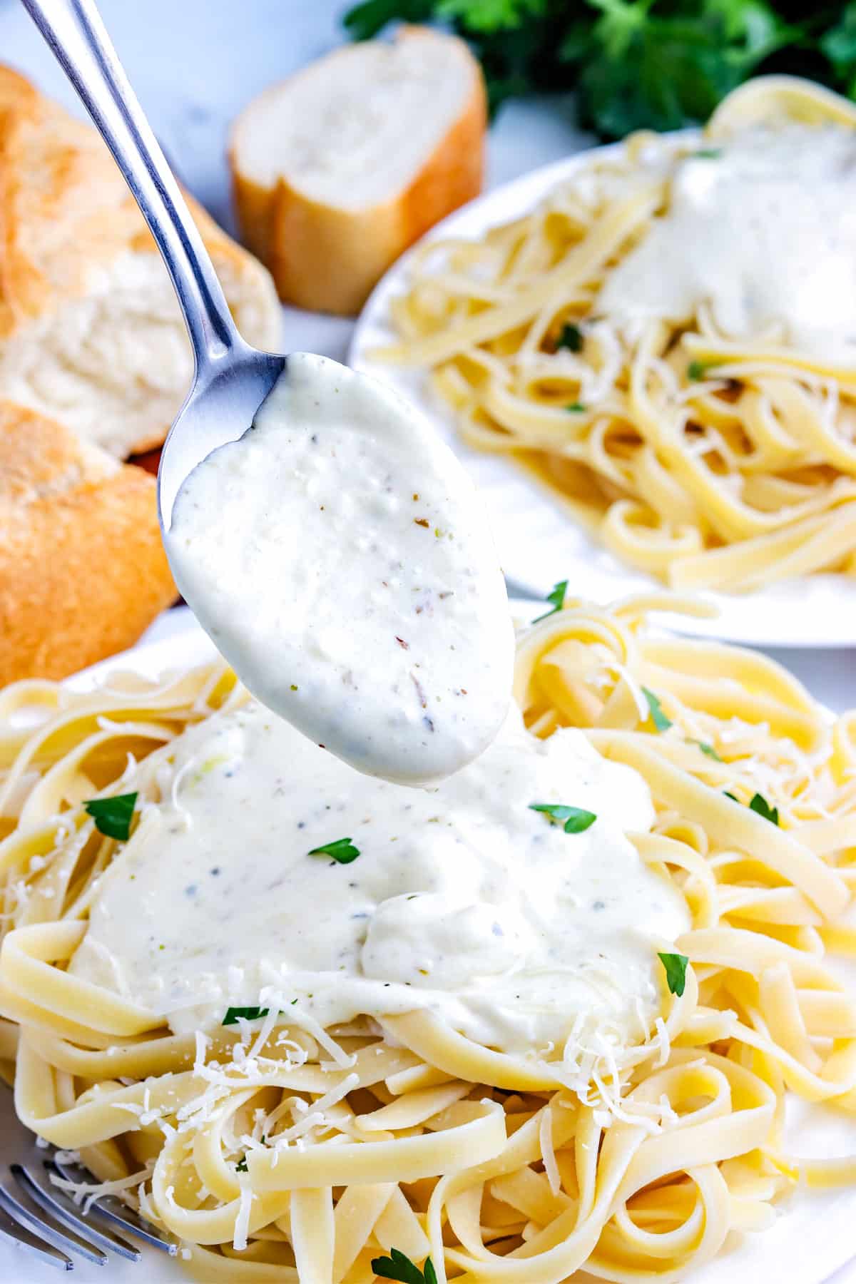 Alfredo Sauce that's made gluten free being spooned over pasta.