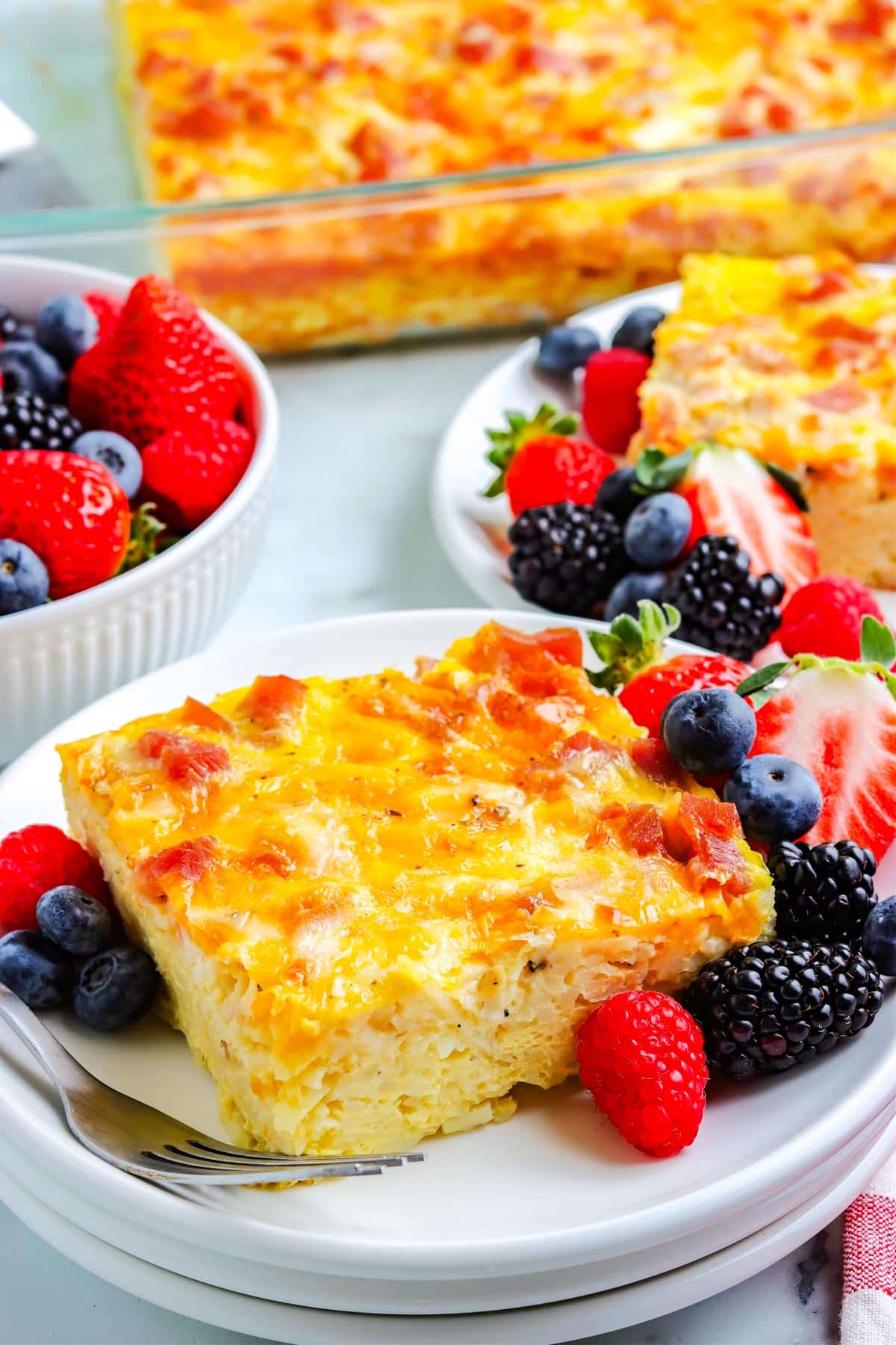 A slice of Ham Breakfast Casserole on a white plate with some berries.