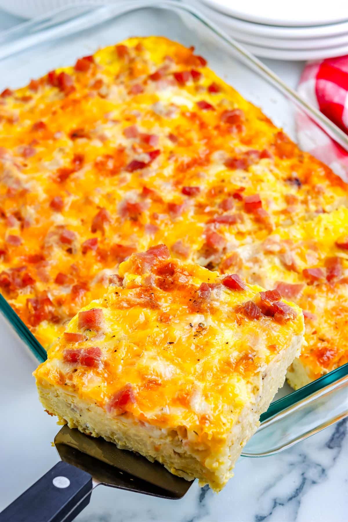 A piece of ham and cheese breakfast casserole lifted from the casserole dish.