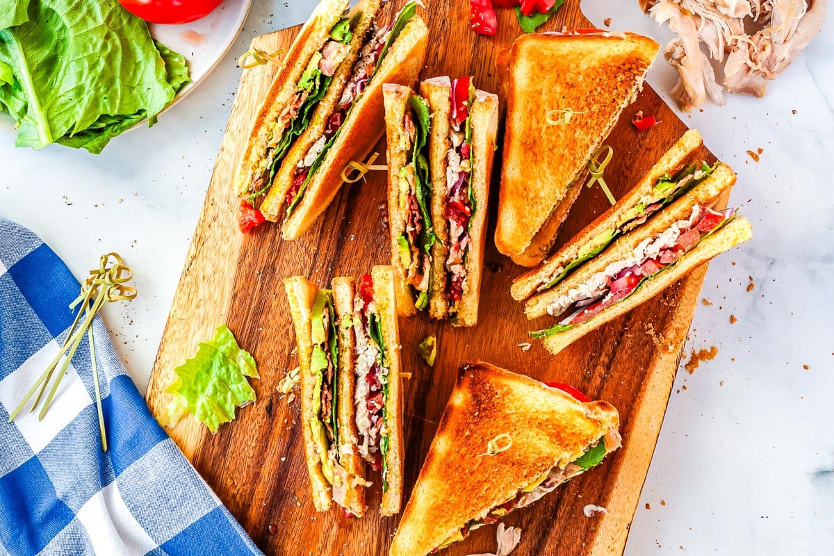 Sandwiched sliced in half on a wood cutting board.