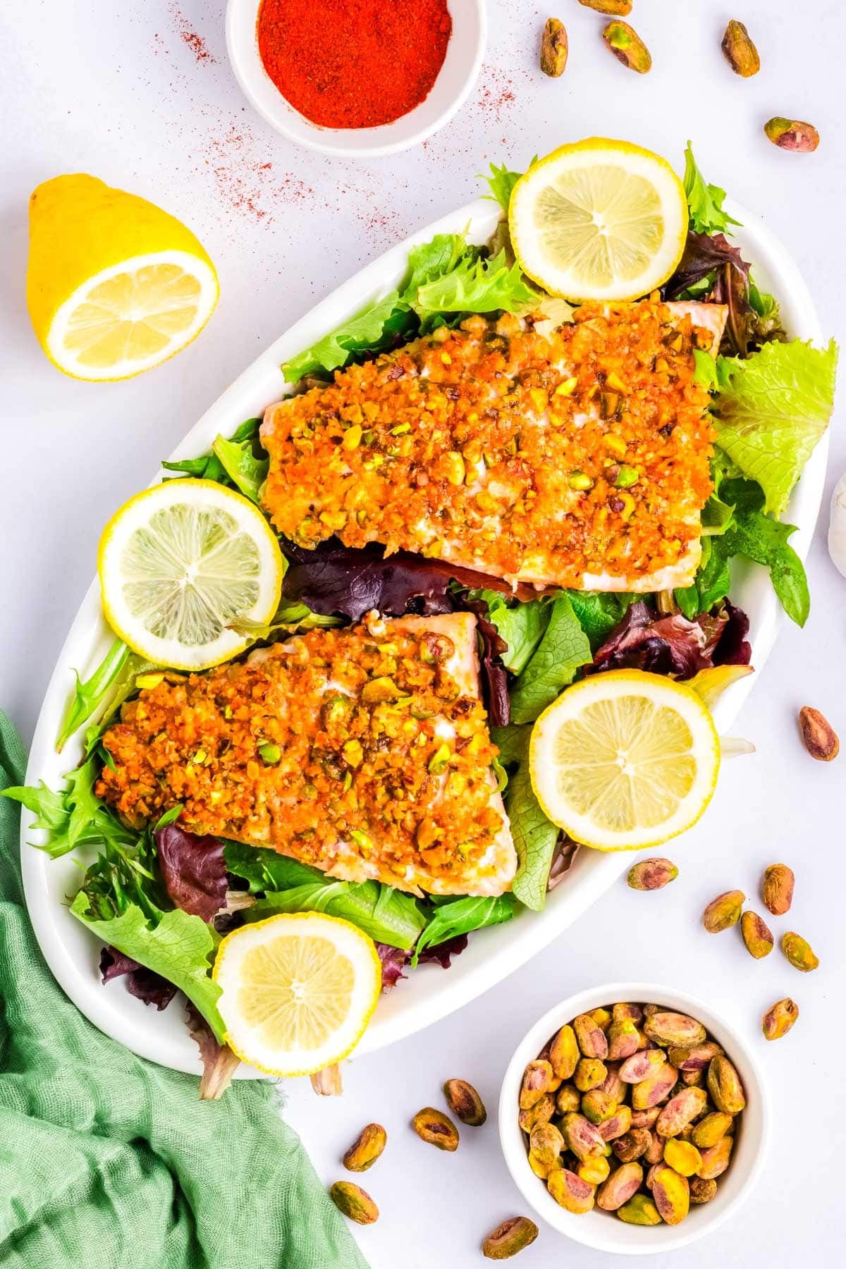 The finished Crusted Pistachio Salmon on a white platter with salad greends.