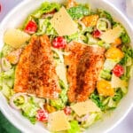 Salmon Caesar salad in a white bowl.