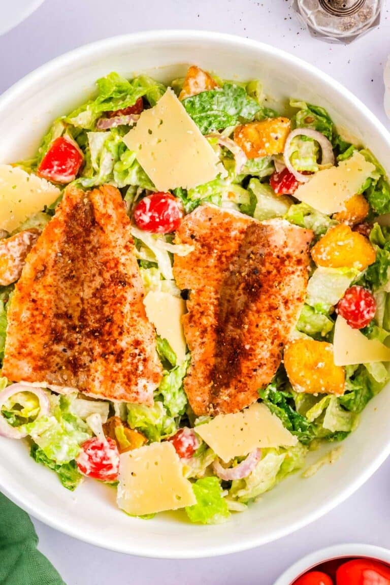 Salmon Caesar salad in a white serving bowl.