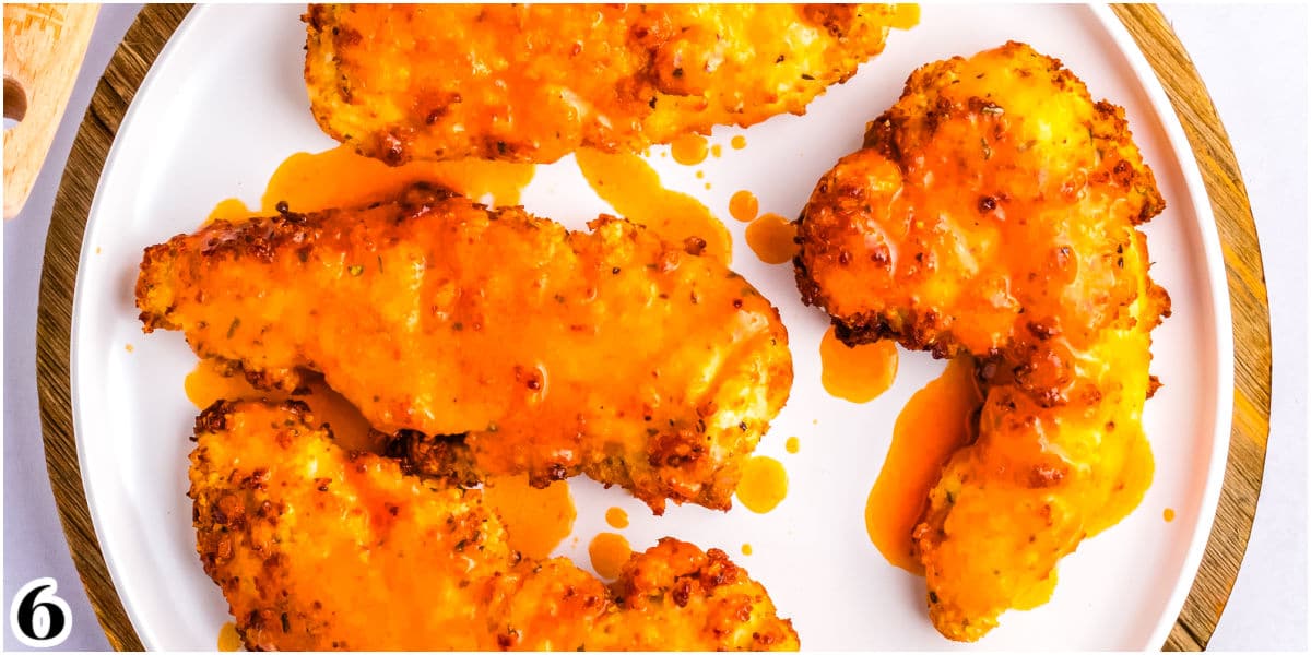Chicken tenders on a plate and brushed with buffalo sauce.