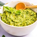 Pesto ina white serving bowl with a spoon.