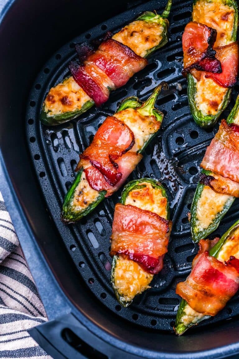 The air fryer bacon wrapped jalapeno poppers in a basket of an air fryer.