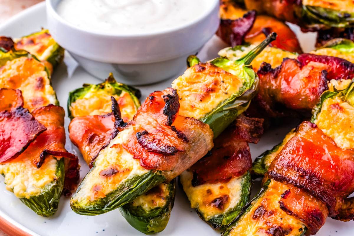A tray of jalapeno poppers with ranch for dipping.