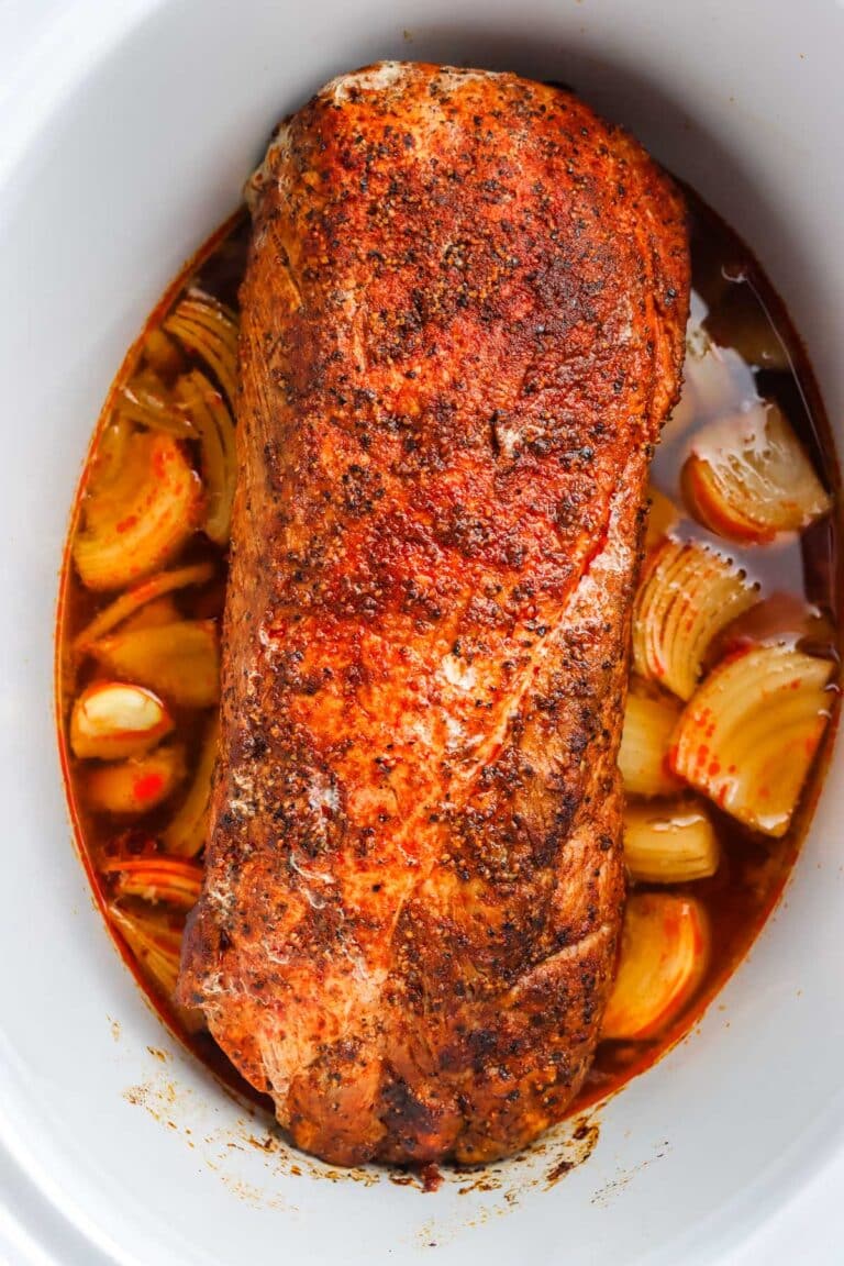 The finished pork loin crockpot recipe in a slow cooker with onions.