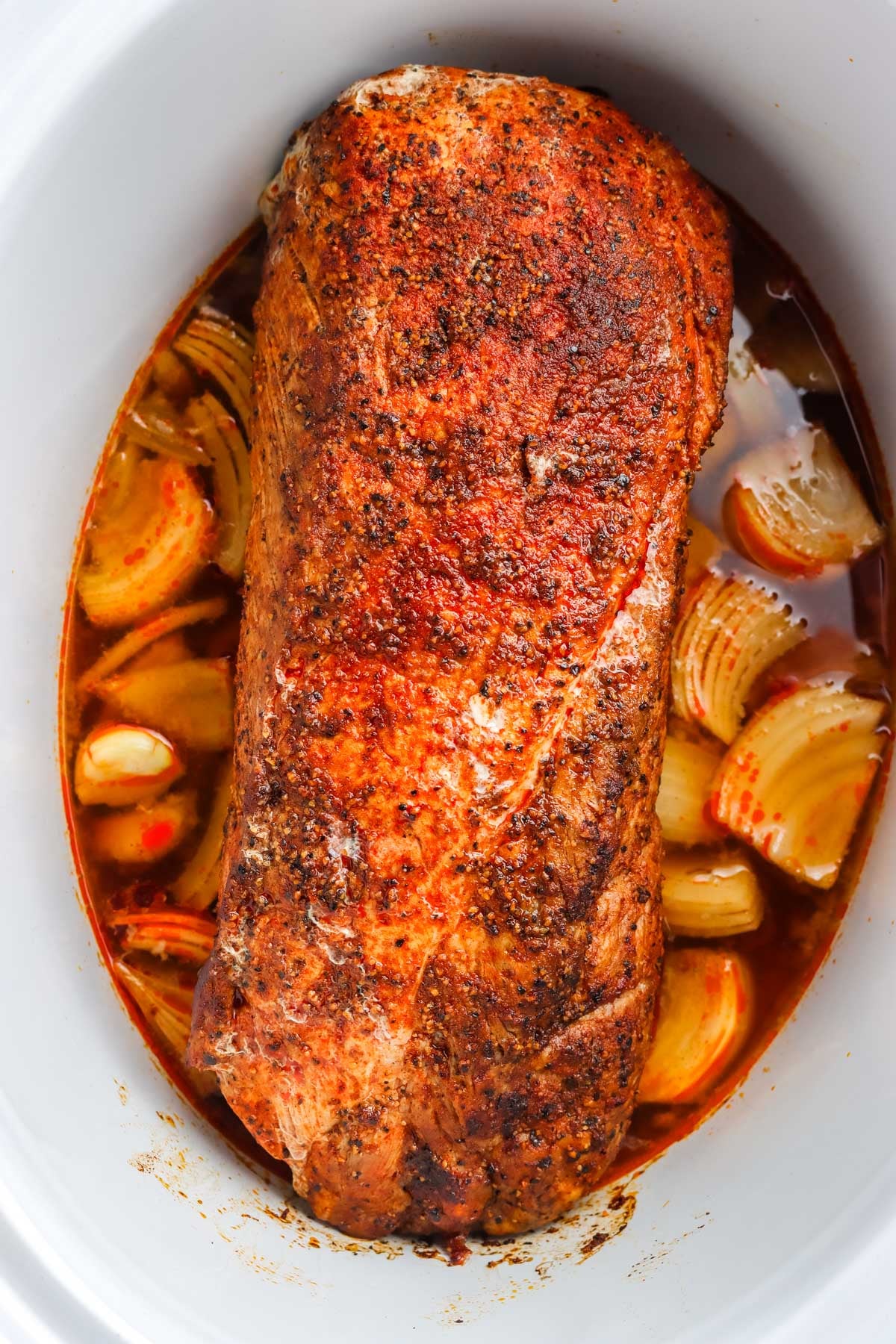 The finished pork loin crockpot recipe in a slow cooker with onions.