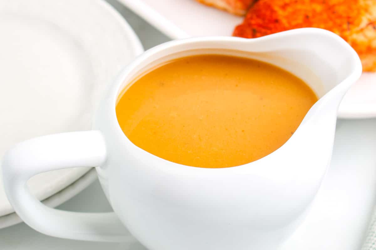 A white gravy boat with the finished pork meat gravy recipe in it.