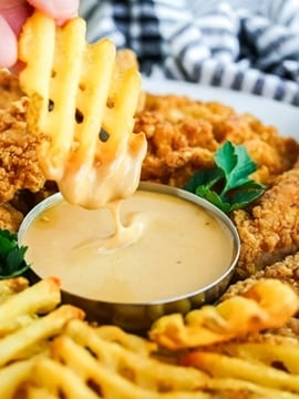 a platter of waffle fries and chicken fingers with Chick Fil A Sauce.