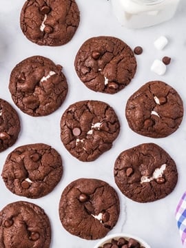 An overhead picture of the finished Chocolate Marshmallow Cookies on a countertop with a glass of milk.