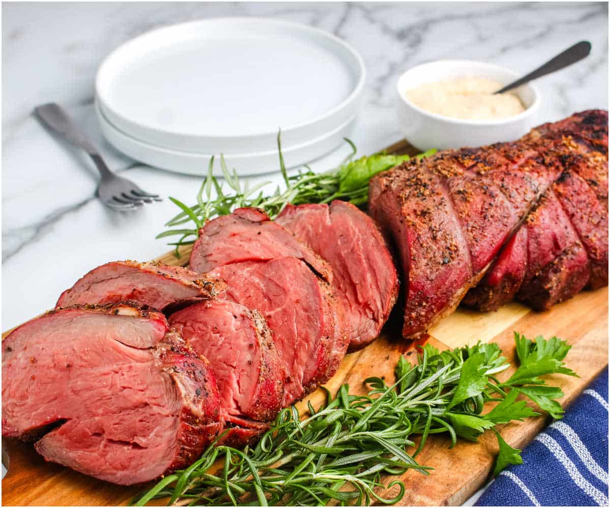 Smoked Beef Tenderloin with horseradish sauce on a cutting board.
