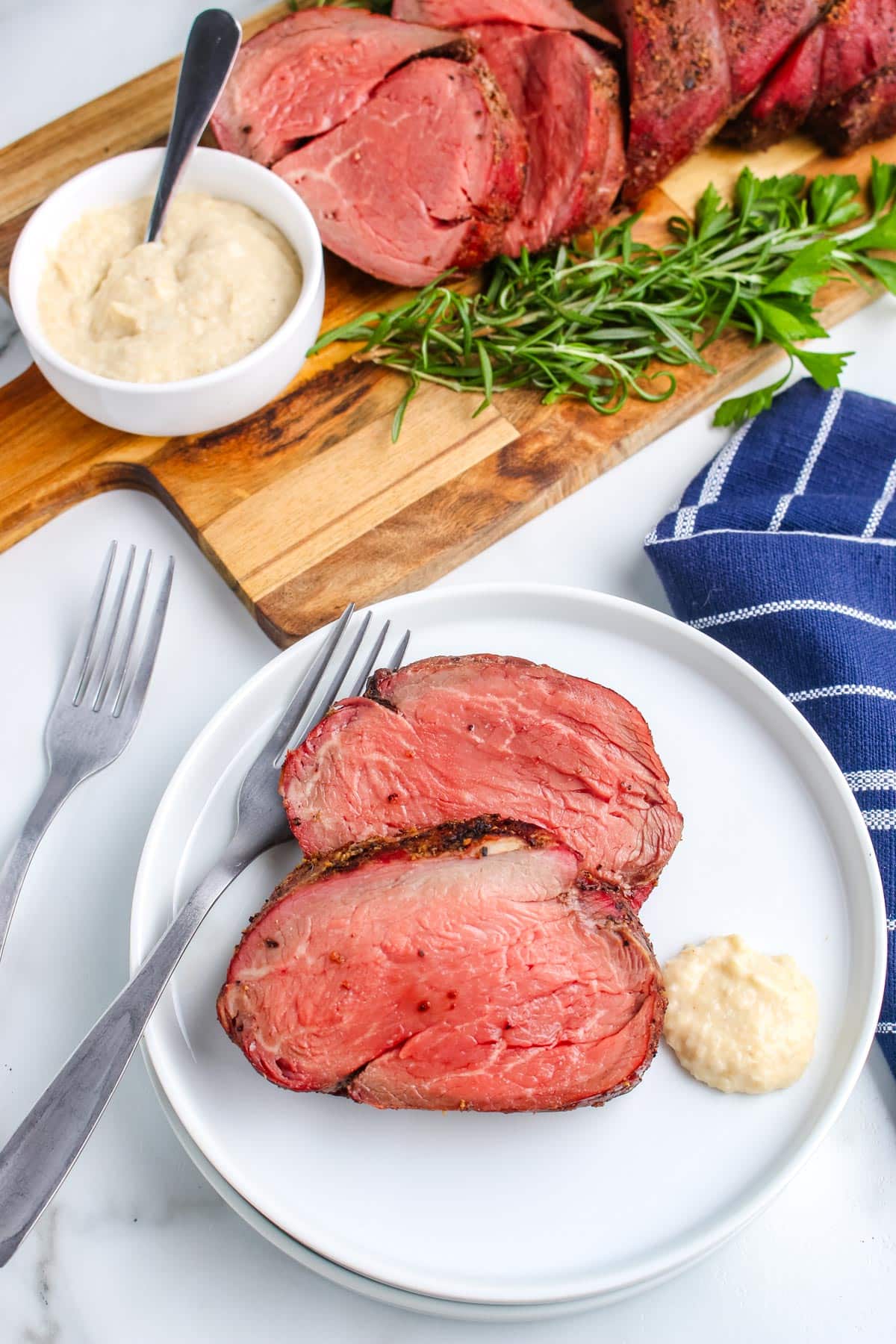 Two pieces of the finished Smoked Beef Tenderloin recipe on a white plate with horseradish.