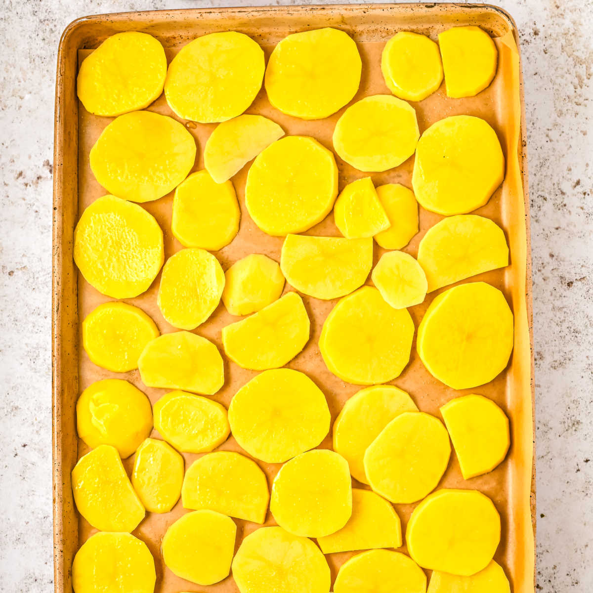 The potatoes on a rimmed baking sheet before baking.