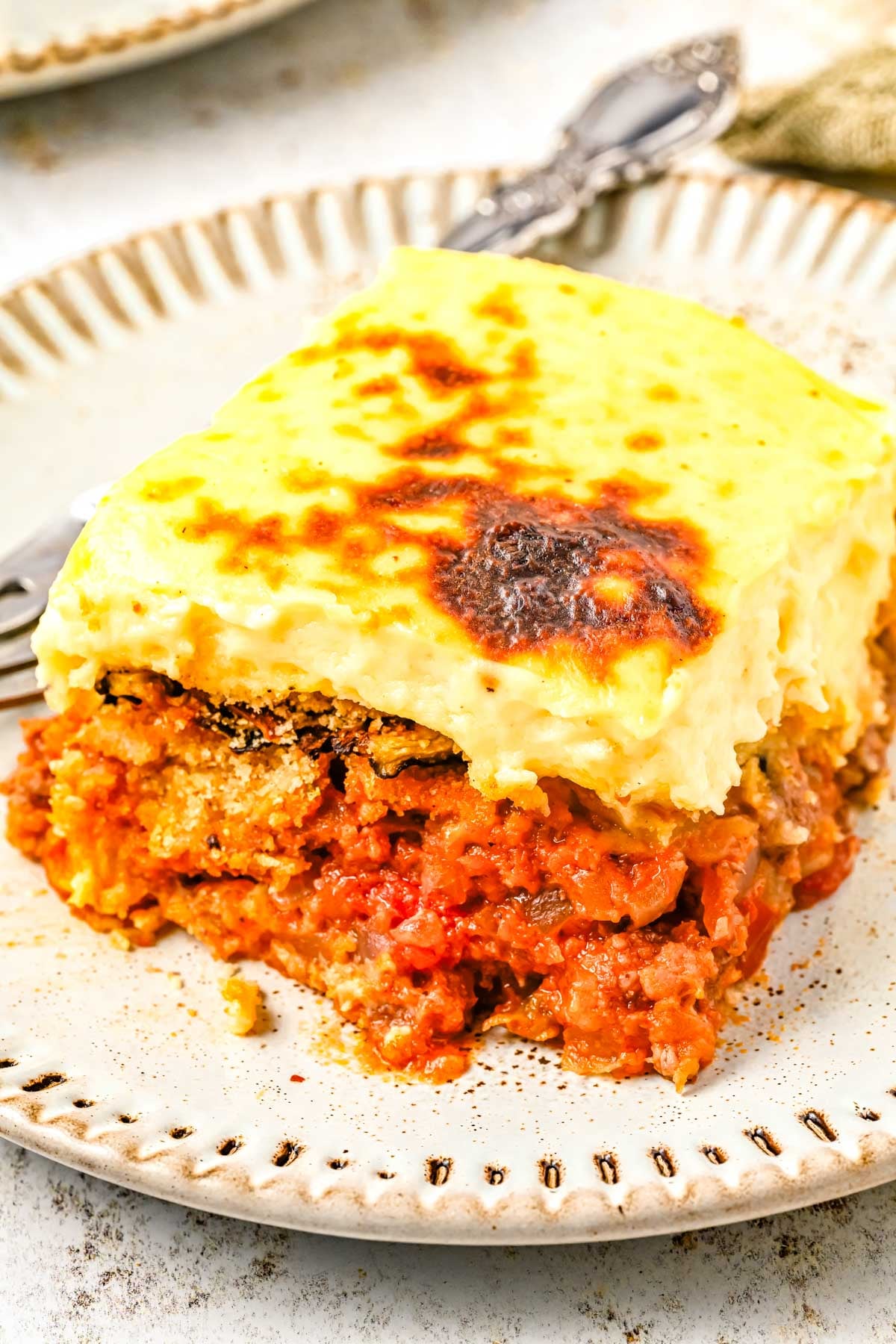 A slice of the finished moussaka recipe on a white plate.