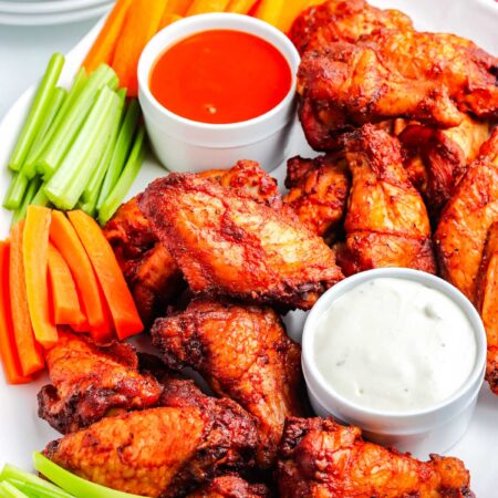 A platter of smoked buffalo wings with blue cheese dressing and buffalo sauce.