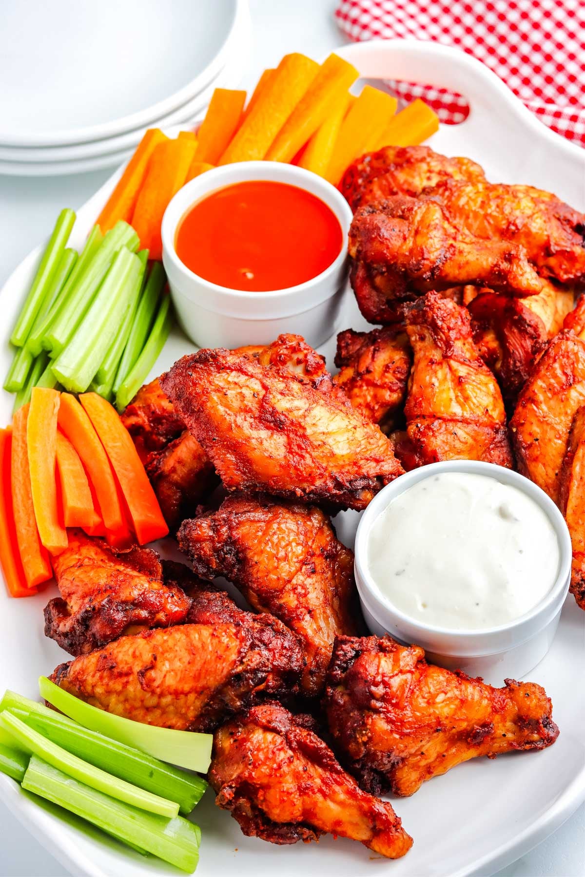 A platter of smoked buffalo wings with blue cheese dressing and buffalo sauce.