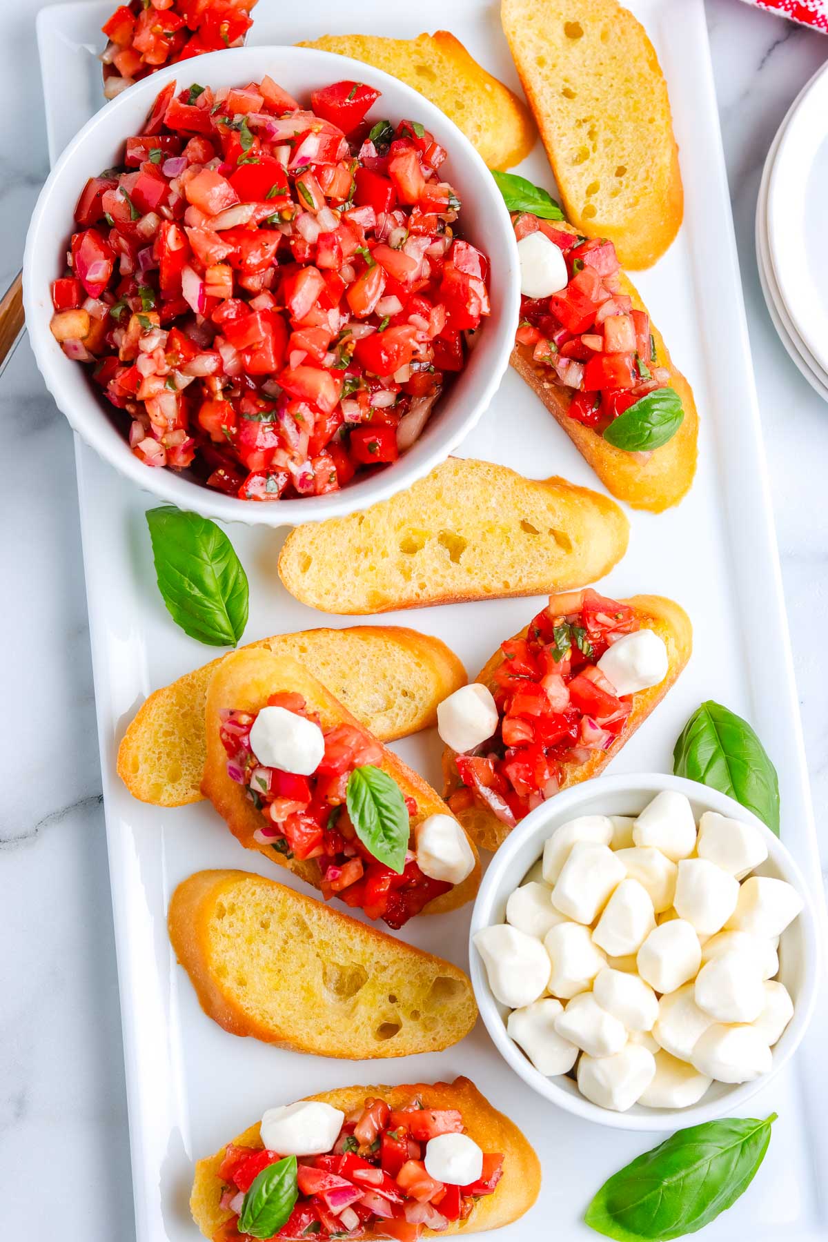 The finished Bruschetta recipe with mozzarella on a white platter.
