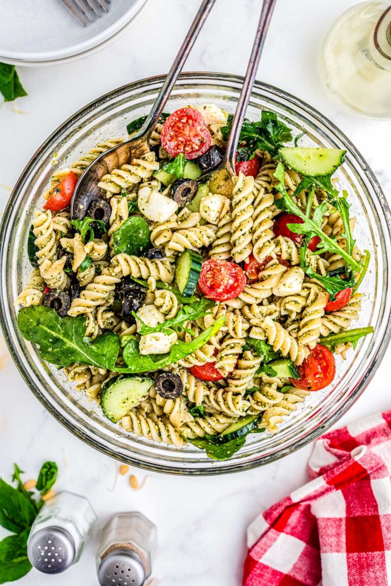 Summer Pesto Pasta Salad in a clear serving bowl with tongs.