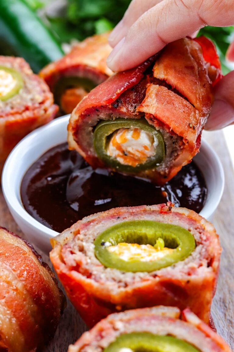 A Smoked Armadillo Egg cut in half and then a hand dipping it into BBQ sauce.