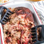 The smoked pulled pork in a pan after it's been pulled apart.