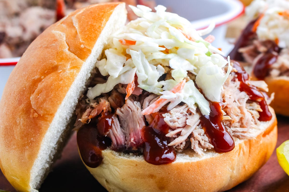 Smoked pulled pork butt on a bun with barbucue sauce and coleslaw.