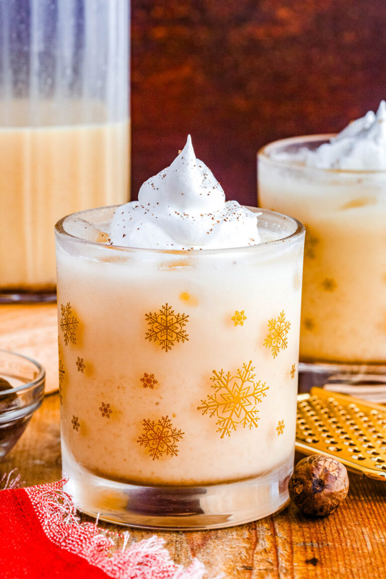 Rich and creamy eggnog in a gold snowflake glass with a swirl of whipped cream on top, perfect for the holidays.